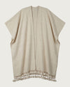 NUBE handwoven Desi wool poncho flat lay, natural ivory tone with oversized tassel hem — Traces of the World
