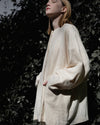 Side profile of the Kala jacket highlighting the unique batwing sleeves and the organic, linen-like texture of the handwoven fabric.