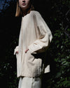 Side profile of the Kala jacket highlighting the unique batwing sleeves and the organic, linen-like texture of the handwoven fabric. 