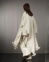 Back view of the nube poncho, emphasizing the two-panel construction and long fringe details. 