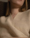 Detail view of the V-neckline on the Silence poncho, showing the organic open weave of the Khadi silk and wool blend. 